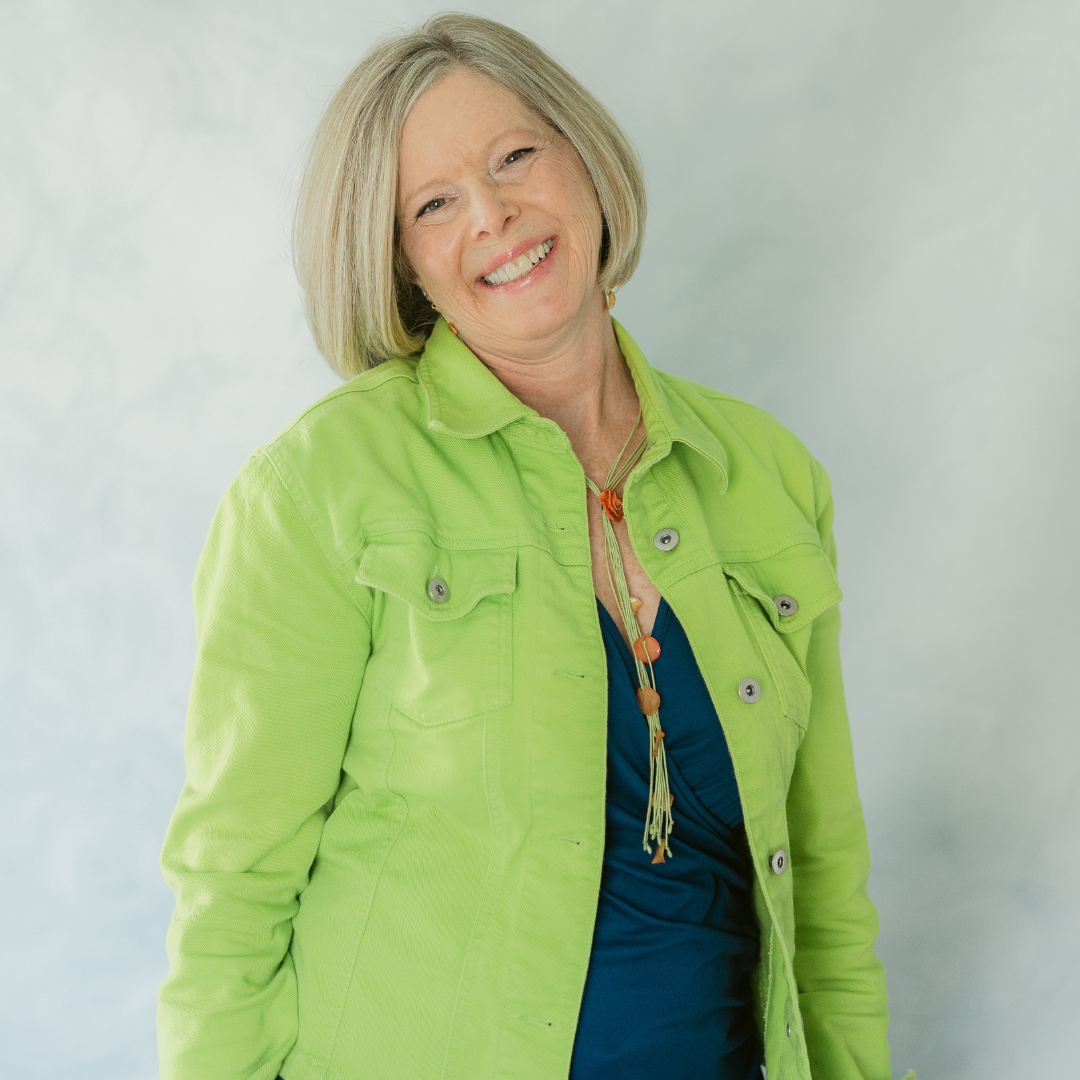 blonde woman in bright green jacket and blue shirt smiling big
